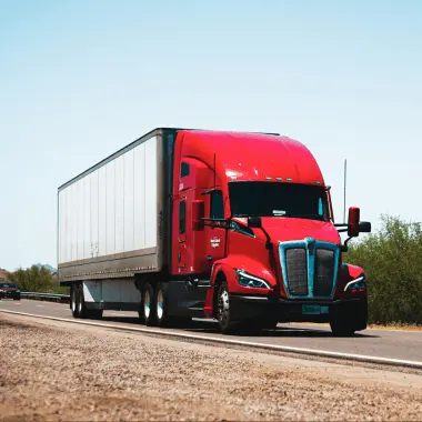 Red transport truck hauling a trailer on the highway